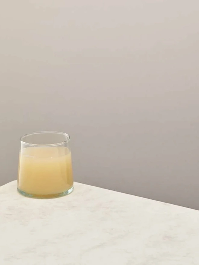 Low Glasses (Set Of 1 Or 4), a low glass sitting on a white counter top against a plain backdrop. It is filled by a soft drink. 