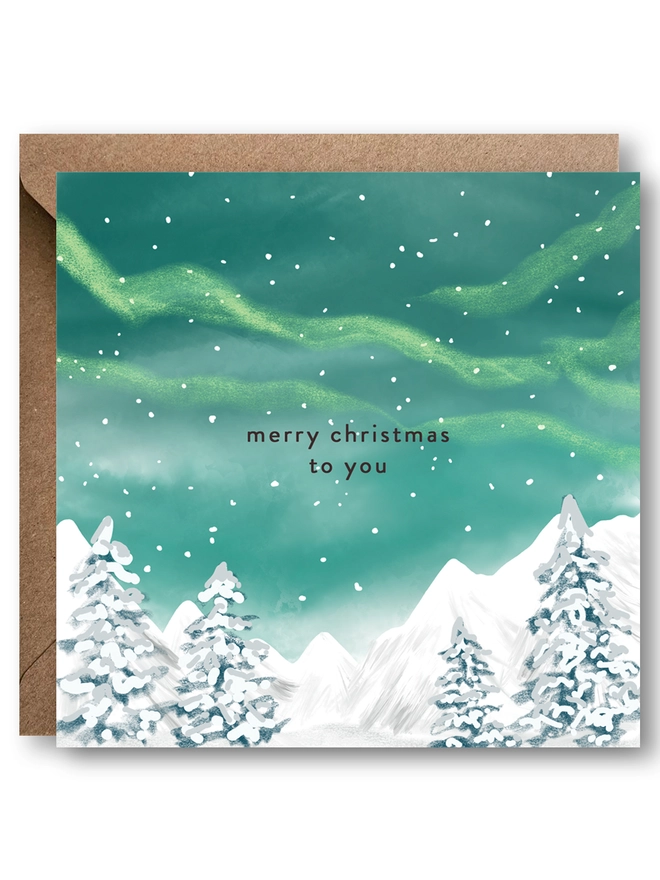 Christmas Card with the message merry Christmas to you, on a snowy trees and green northern lights sky background