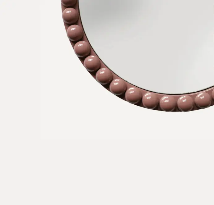 Round oversized bobbin mirror with a decorative bobbin-style wooden frame, hanging on a white wall.