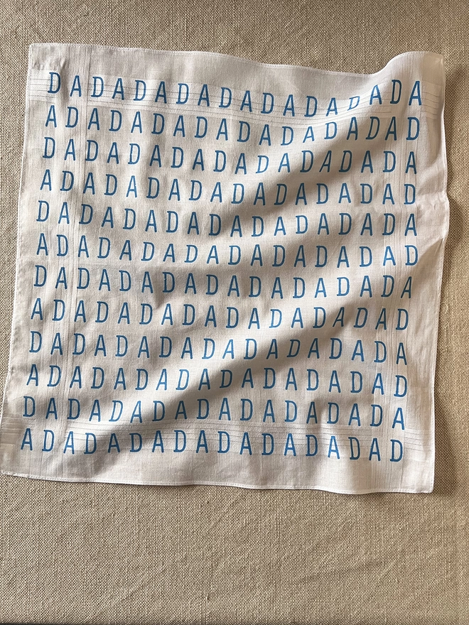 A Mr.PS DADA Hankie laid flat on a linen tablecloth