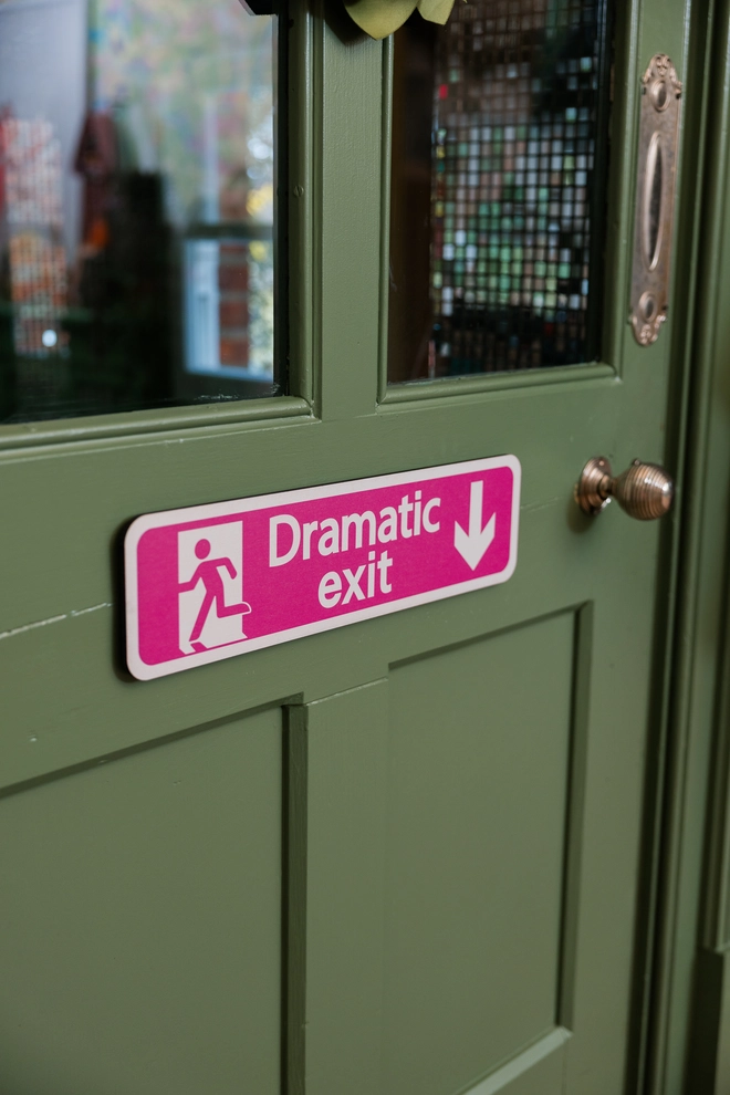 Hot pink Dramatic Exit Sign against an olive green doorway