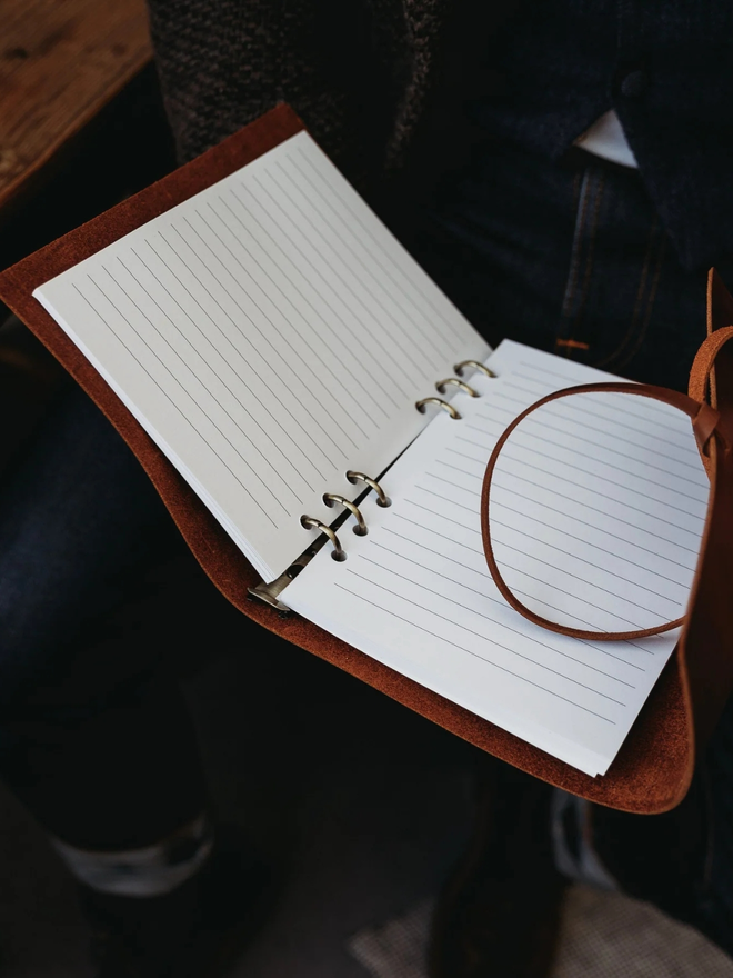 leather refillable ring binder. an open leather ring binder showing paper and ring mechanism inside.
