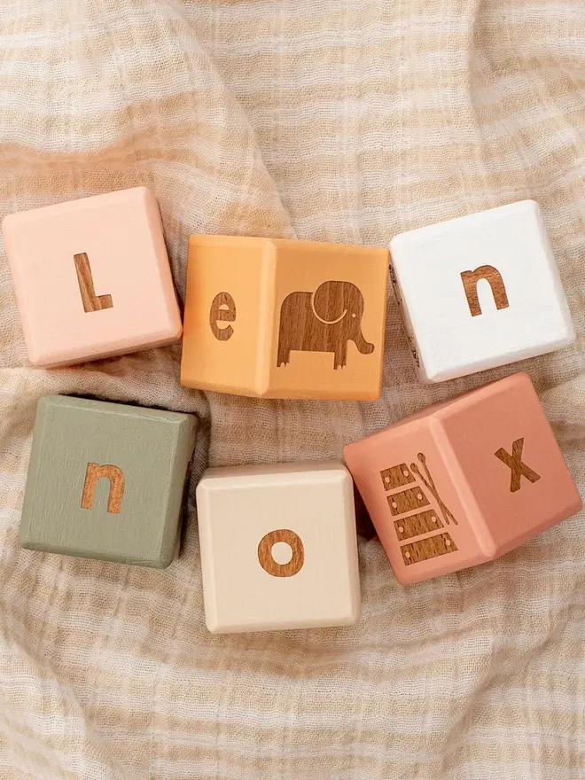 wooden baby letter blocks. a selection of square wooden blocks with engraved letters and illustrations, in various colours. 