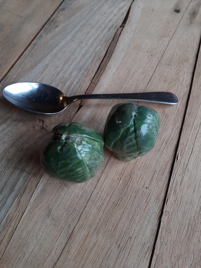 Unique artisan Brussels sprout ceramic shakers for salt and pepper, glossy finish, photographed next to teaspoon for size reference