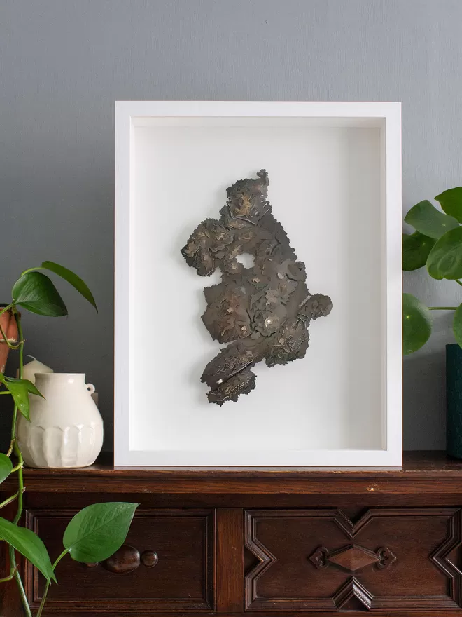 Metal Snowdonia National Park contour map in a white box frame, sat on a wooden mantlepiece 