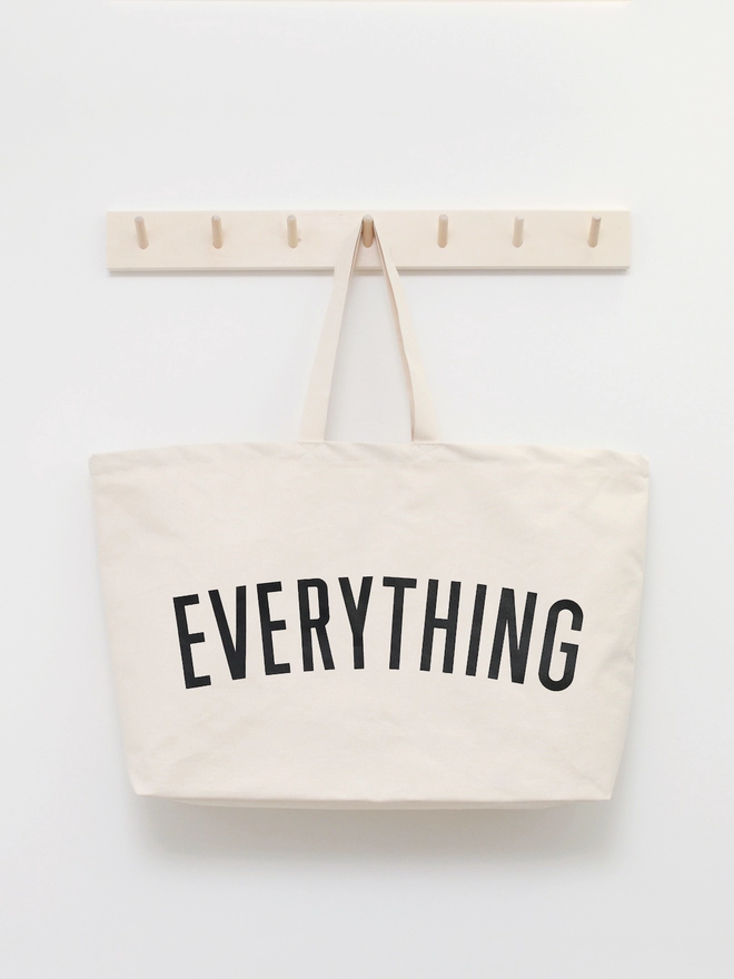 Everything oversized tote bag in natural canvas hanging on coat rack