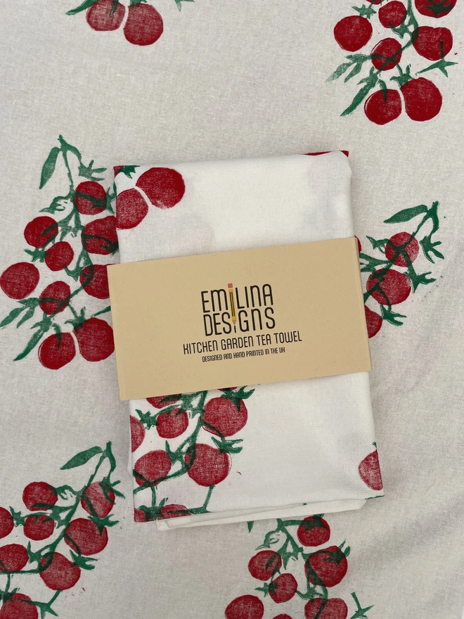 Tomatoes Kitchen Tea Towel. White fabric with a diagonal pattern of red tomatoes.