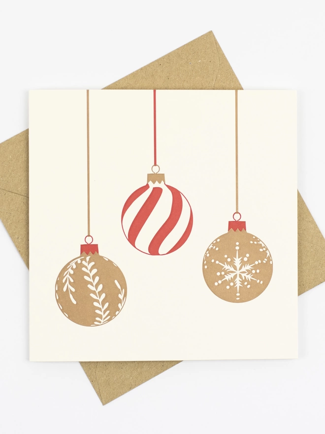 Three baubles dangling from ribbon, two gold with red tops and one with red swirls