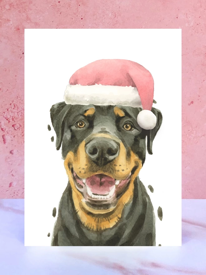A Christmas card featuring a hand painted design of a rottweiler, stood upright on a marble surface. 