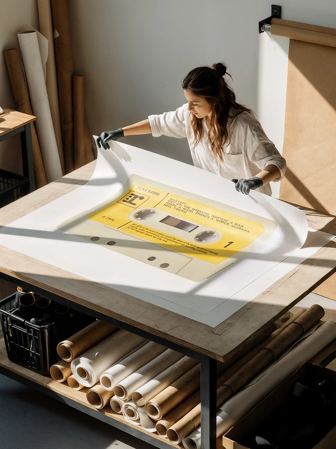 neil young harvest cassette tape print. artist unrolling print on studio desk.