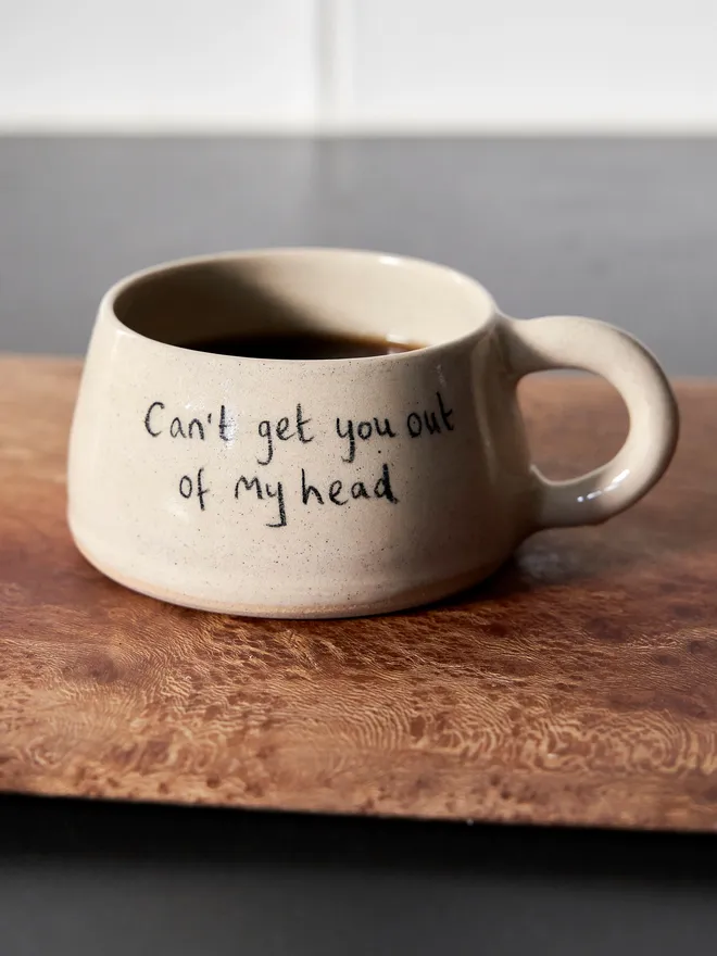 Cream ceramic mug with the words 'Can't Get You Out of My Head' written on it 