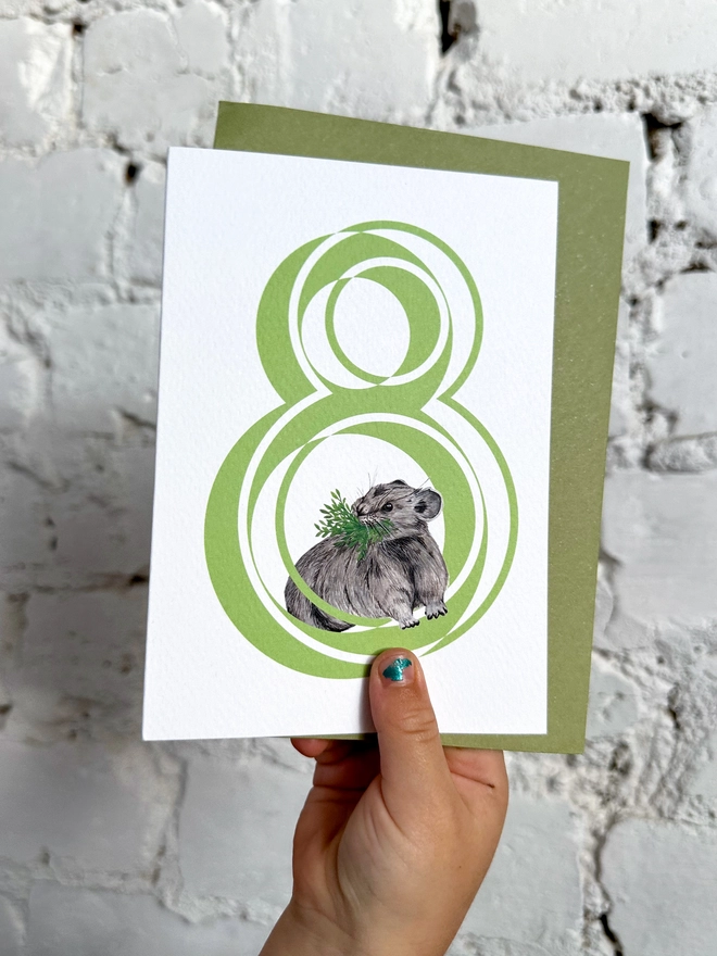 white card with a big green number 8 and a cute little pika illustration with a green envelope