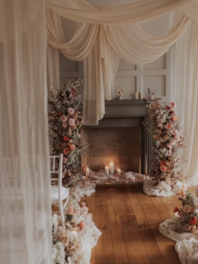 Ikebana, ceramic vase pictured in a florally decorated room with drapes and candles burning. 