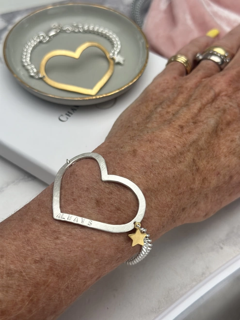 model wears a personalised large open heart charm in silver on chunky curb chain with a small gold star charm, gold version in the background