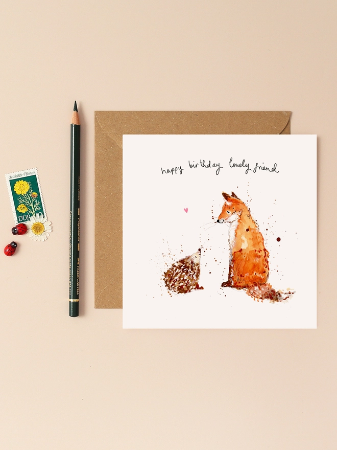 A heartwarming illustration featuring a friendly hedgehog and a curious fox, both with joyful expressions. The hedgehog, with its spiky quills, stands beside the fox, whose bushy tail adds a playful touch. Above them, the handwritten message "Happy Birthday Lovely Friend" conveys a warm and personal sentiment. The design combines soft, earthy tones and charming details, capturing the essence of a cherished friendship.