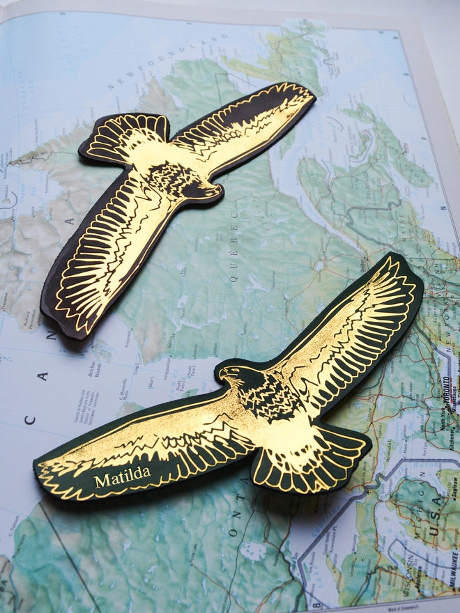 a pair of personalised American bald eagle leather bookmarks made from sustainably produced vegetable tanned leather and hand dyed in brown and forest green by Natthakur