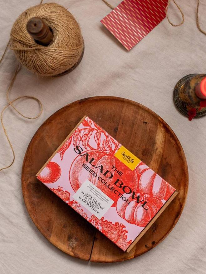 the salad bowl seed collection. box in pink and red packaging with illustrated tomatoes photographed in wooden dish on countertop.