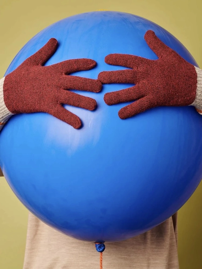 Block Lambswool Gloves, a person wearing colourful globes holding a large ball. 