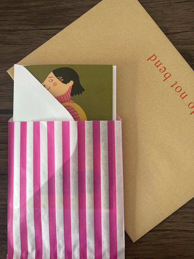 Illustrated card packed with a white envelope inside a paper bag
