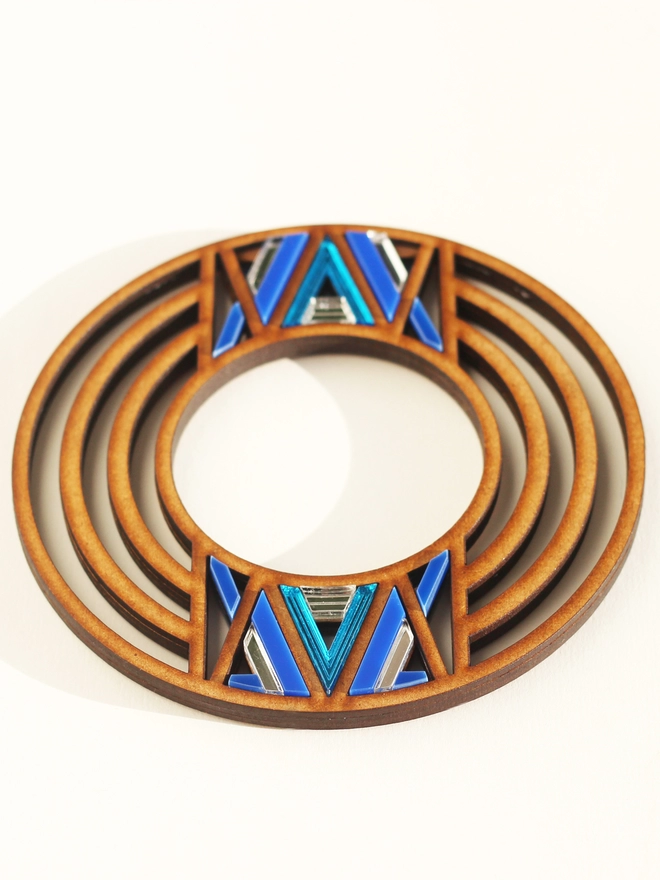 A full image of a intricate bangle, multi ringed bangle with geometric acrylic pattern in the middle 