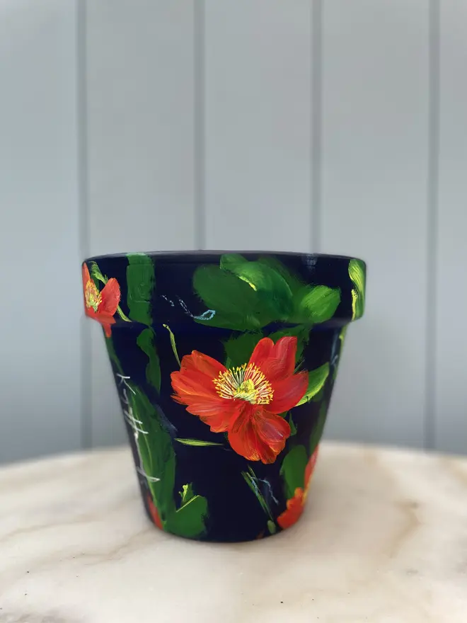 Unique hand-painted terracotta pot featuring orange Icelandic poppies on a deep rich blue background