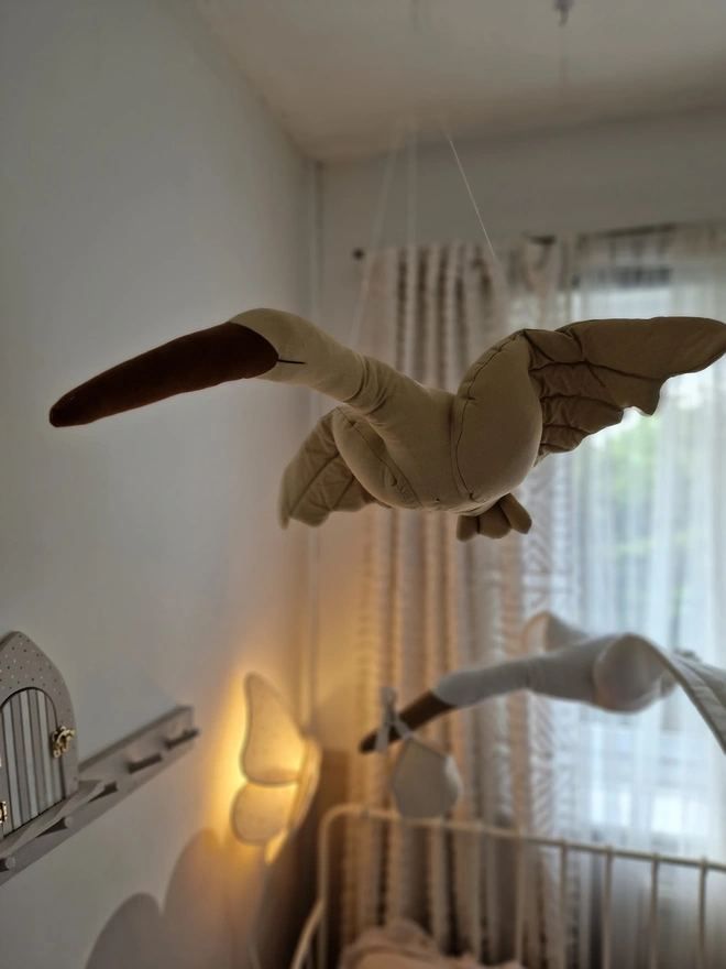 Flying Swan Hanging Decoration, a hanging beige swan decoration, suspended in a child's bedroom. 