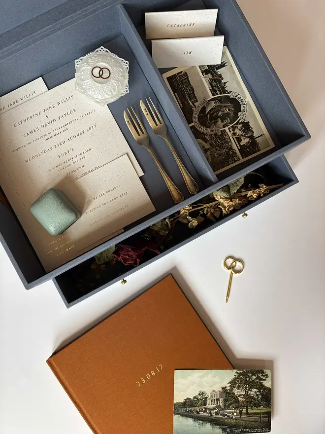 Open wedding keepsake box showing divided top tier, open drawer, guestbook and wedding ephemera