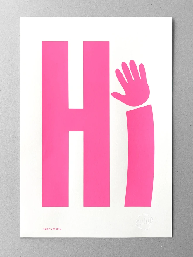 An A3 piece of paper sits on a grey background, with a neon pink screenprinted Hi - the i is a waving hand - the Salty’s stamp is in the bottom right corner.