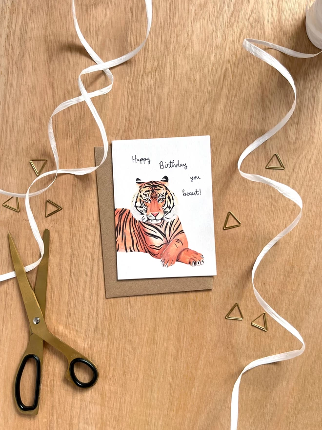 greetings card featuring a tiger with their front paws crossed with the phrase “happy birthday you beaut”