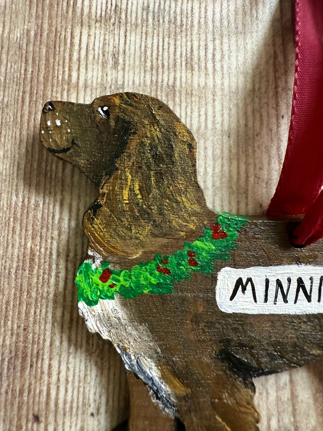 Close up of a Working Cocker  Spaniel Handpainted Christmas Decoration in Chocolate Brown with the name Minnie painted on and hung with red velvet ribbon 