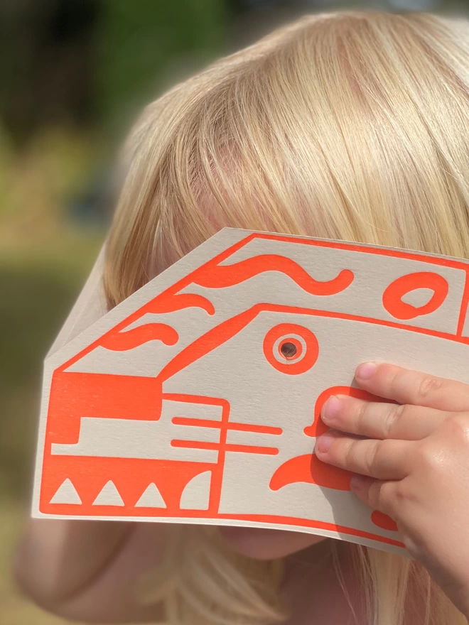 Girl holding Tiger head card in front of her face.