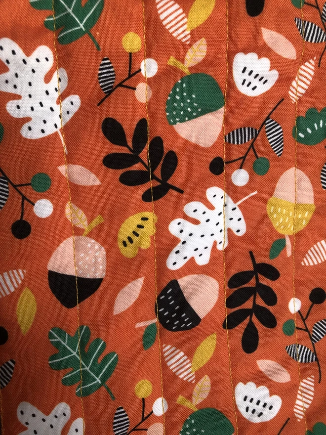 Orange Autumn Leaf Design Print Back to Autumn Leaf Stripe Baby Quilt. A multicolour print with orange background and black, green, yellow, white and pink.
