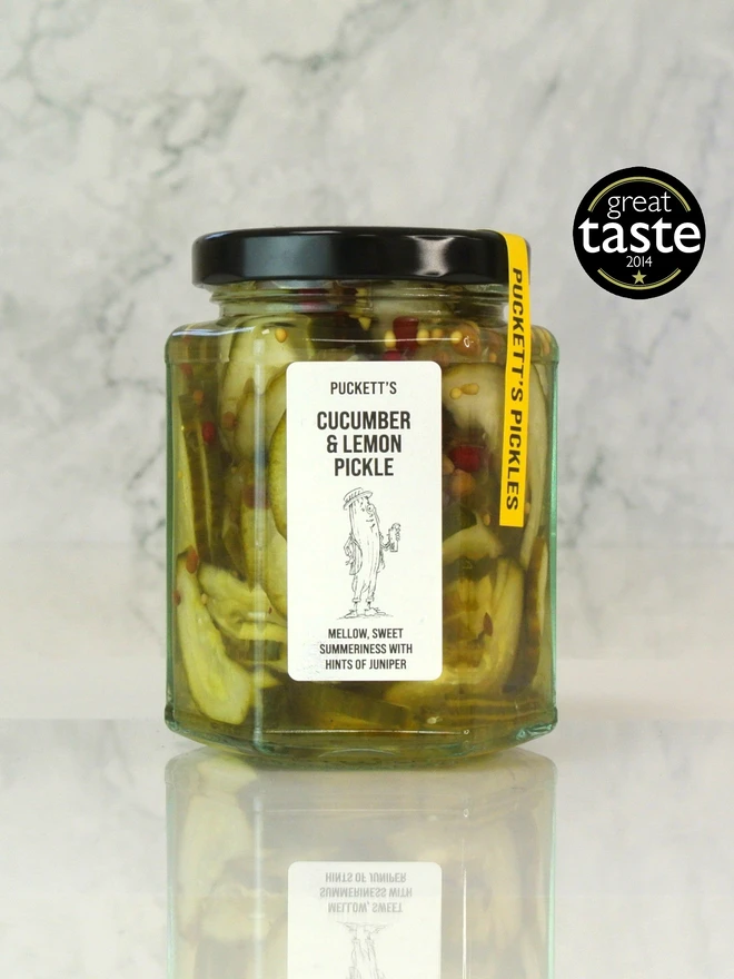 cucumber and lemon pickle. a jar of pickled cucumbers photographed on a marble bakcground.