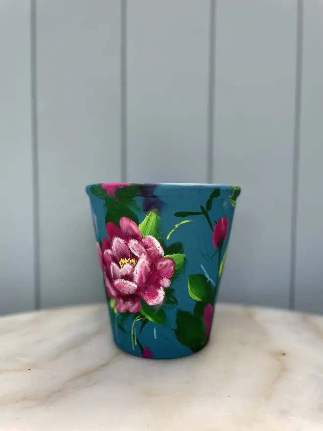 Unique hand-painted terracotta pot featuring pink peony on a turquoise background