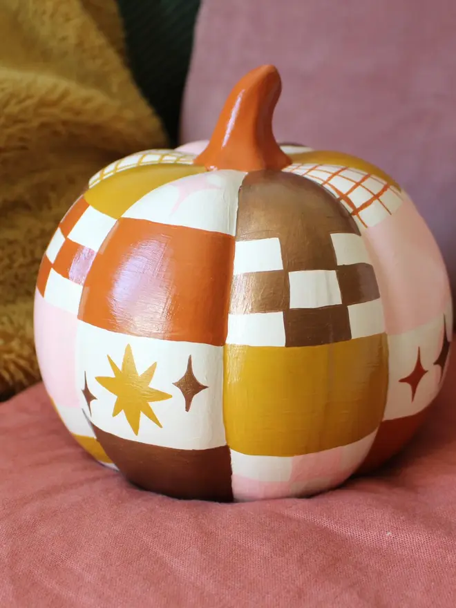 hand-painted celestial patchwork ceramic pumpkin. a ceramic pumpkin painted with patchwork colours of gold, pink, brown and stars and moons.
