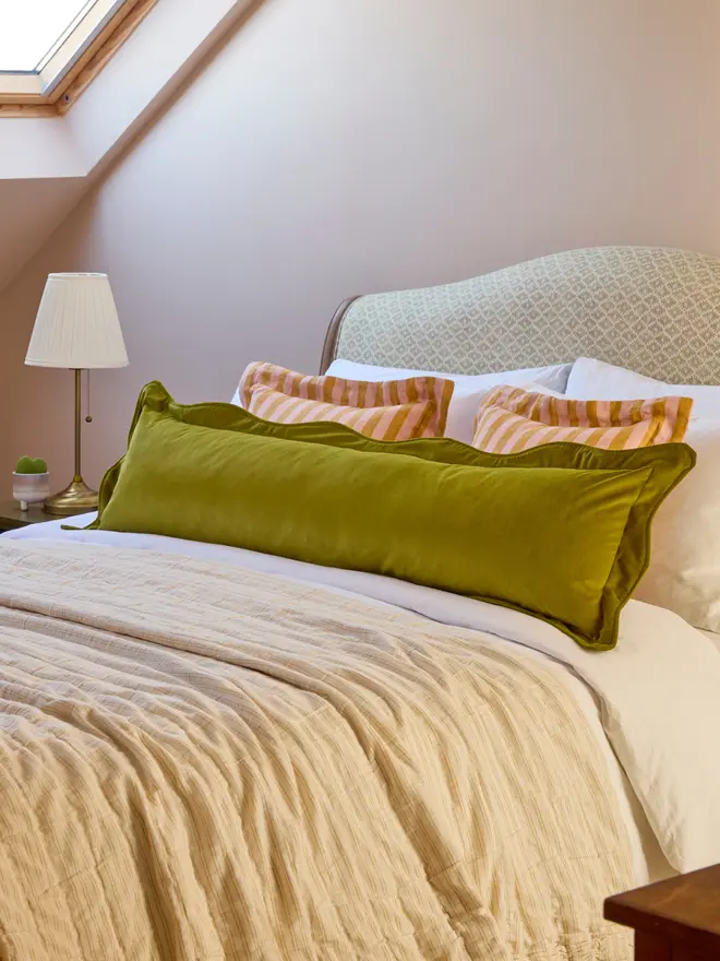 Handmade scalloped velvet bolster cushion 130cm with feather pad paired with stripe linen cushions on bed, Kika Bespoke