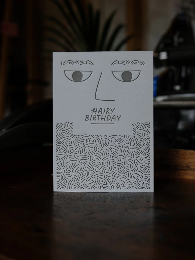 Light grey letterpress printed bearded man card on shelf.