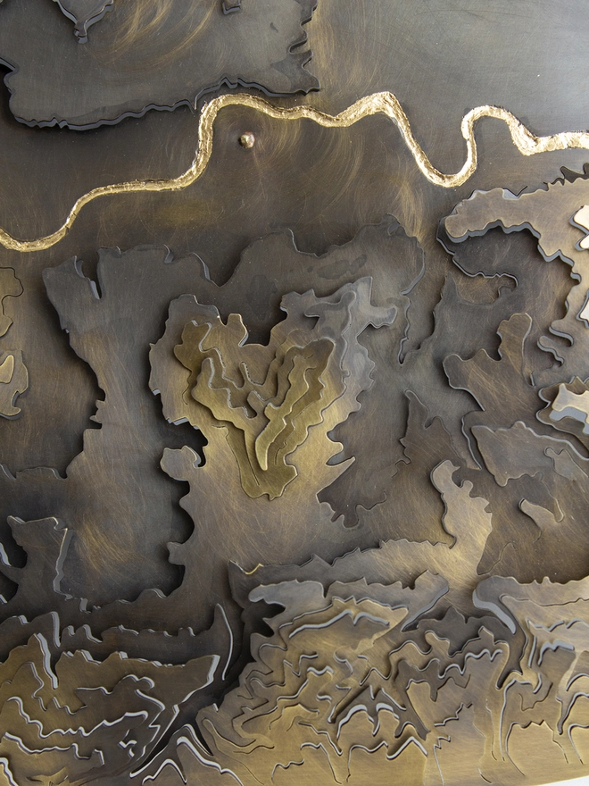 close up of the brass London contour map with engraved gold leaf filled Thames river
