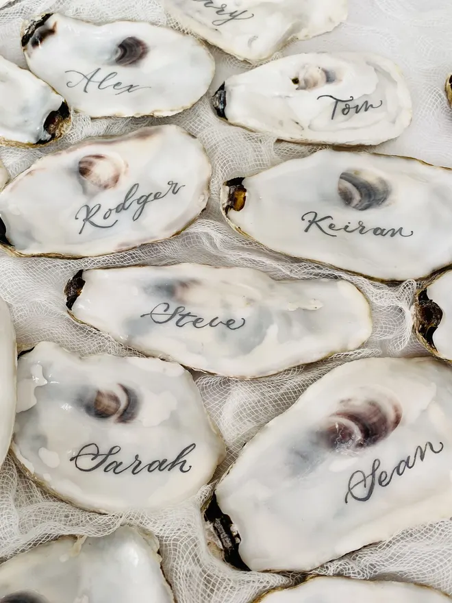 flat oyster shell place cards with names written in calligraphy