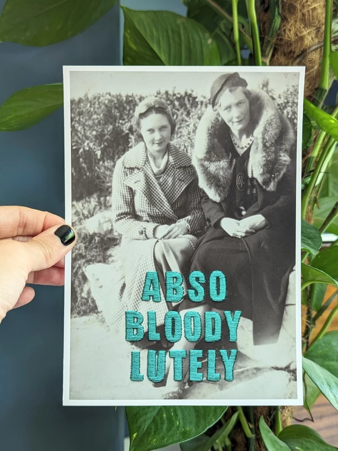  B&W photo of 2 women with Abso-bloody-lutely in teal embroidered across, print version
