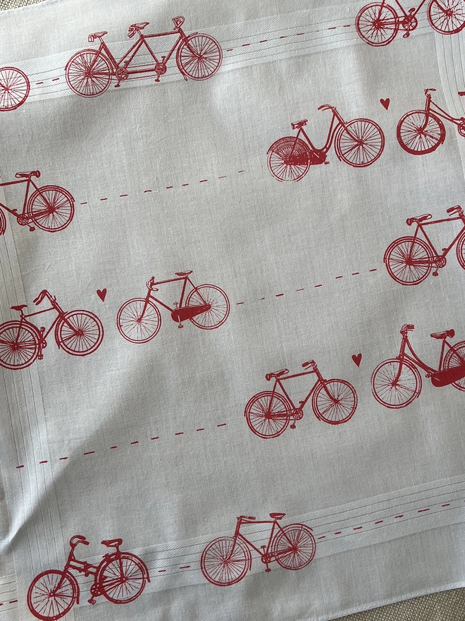 Detail of A Mr.PS white cotton handkerchief printed with a pattern of vintage bicycles with little hearts in coral red