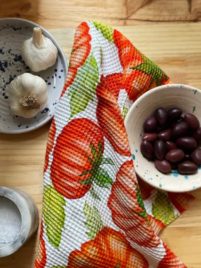 Tomato Waffle Tea towel, next to olives and garlic. 