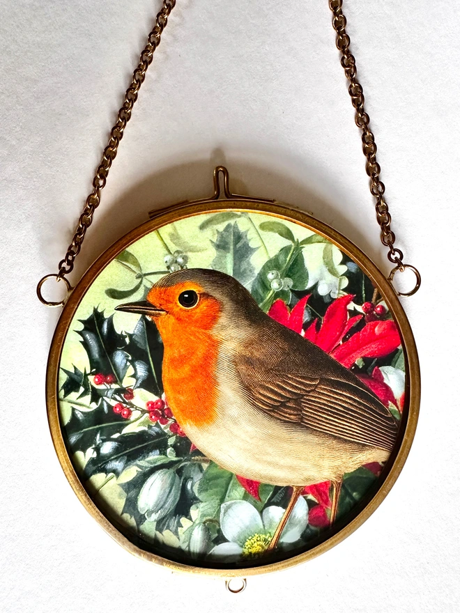 A robin amongst Christmas foliage miniature print in a gold, brass hanging frame.