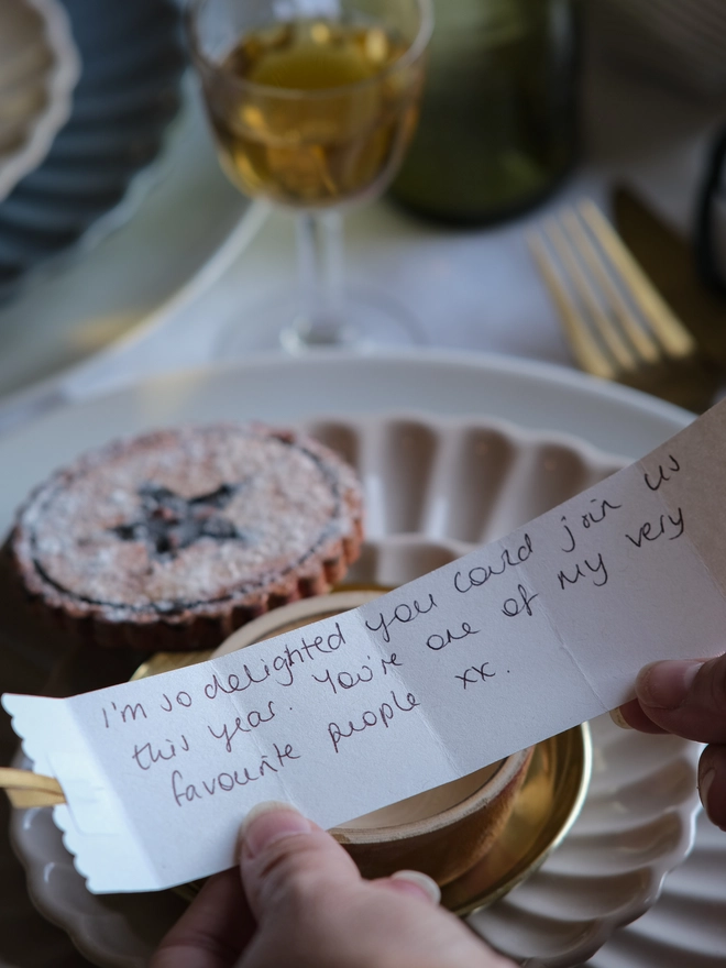 A festive handpainted wooden mince pie place setting with handwriten note to welcome your guests at the Christmas table
