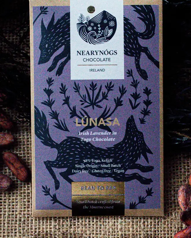 Lúnasa Lavender Chocolate Bar, a chocolate bar sitting on a fabric surface. It is accompanied by some nuts. 