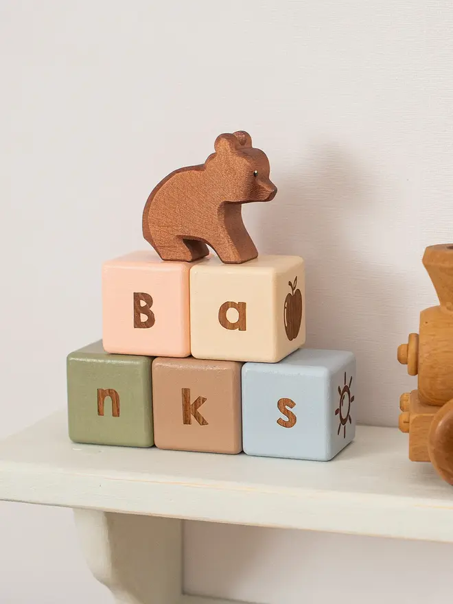 wooden baby letter blocks. a selection of square wooden blocks with engraved letters and illustrations, in various colours. 