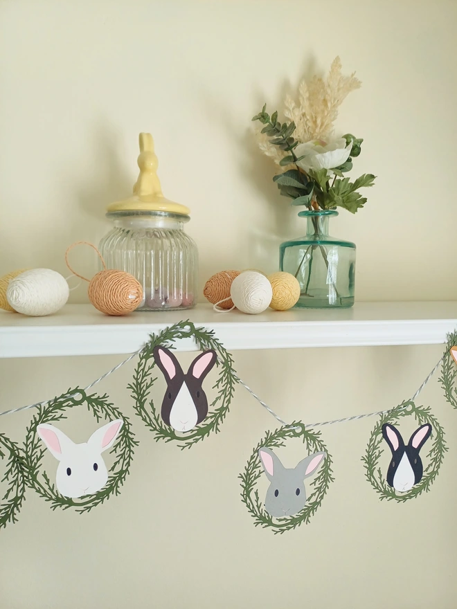 Easter bunny garland looped along a sheld decorated with flowers and easter eggs. (12 bunny option)