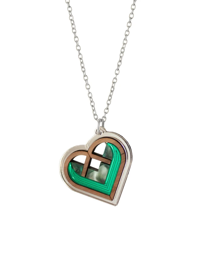 green and silver heart necklace on white background
