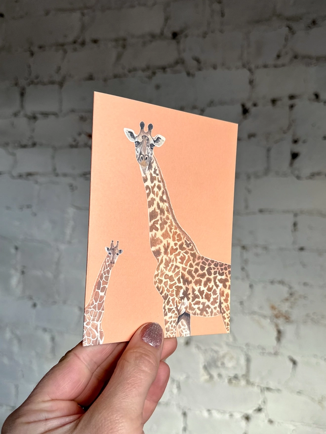 an orange greetings card featuring illustrations of two giraffes