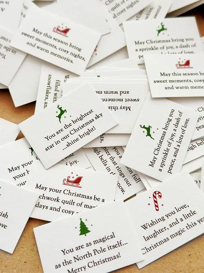 A pile of tiny Christmas wish cards, each with a festive illustration and a written Christmas wish on.